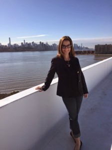 CSM Art & Frame owner Caryn Krueger in front of NYC skyline. 